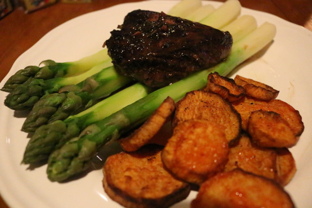 Bifteck juteux nappé d'une riche sauce au vin rouge, patate douce croustillante et asperges vertes fraîches