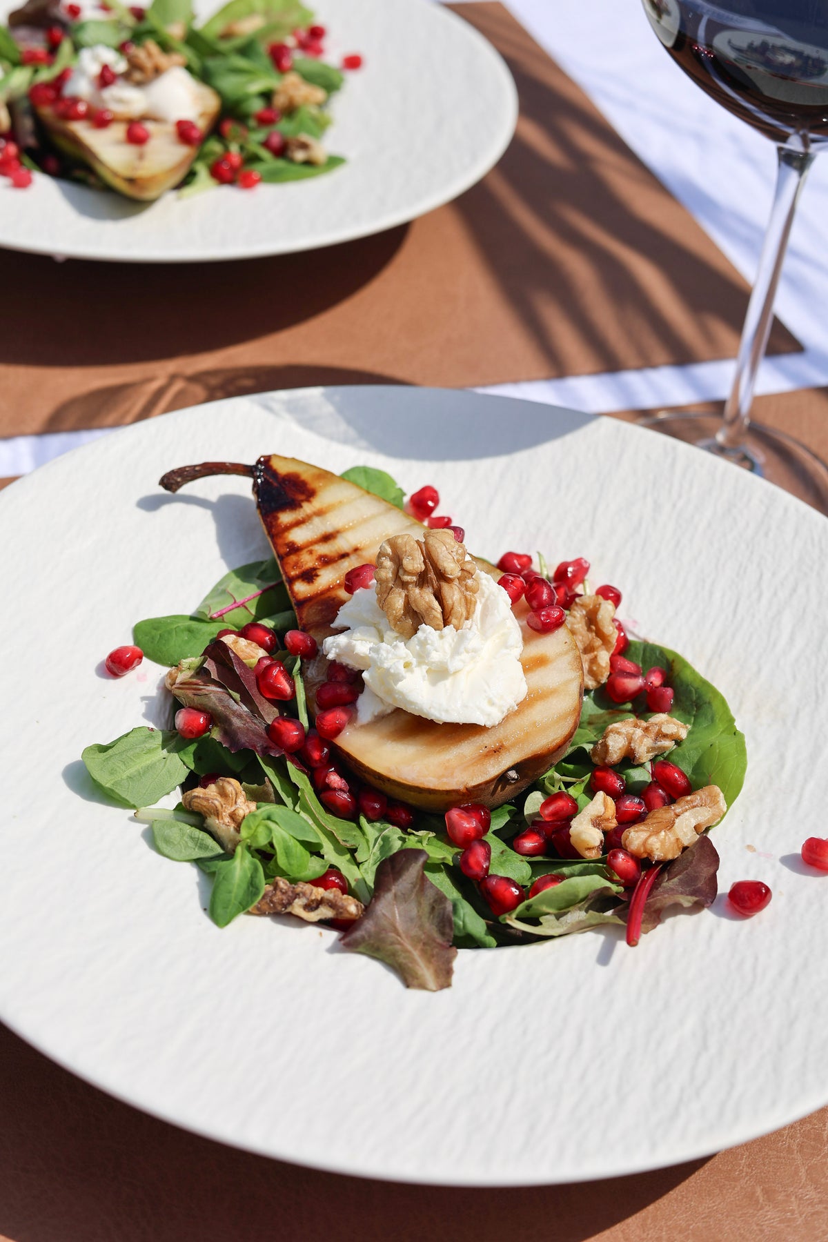 Poire grillée chaude sur un lit de salade, mascarpone onctueux, noix croquantes et graines de grenade fraîches.